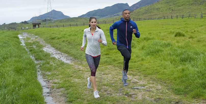 Male and female running on countryside trail in New Balance gear