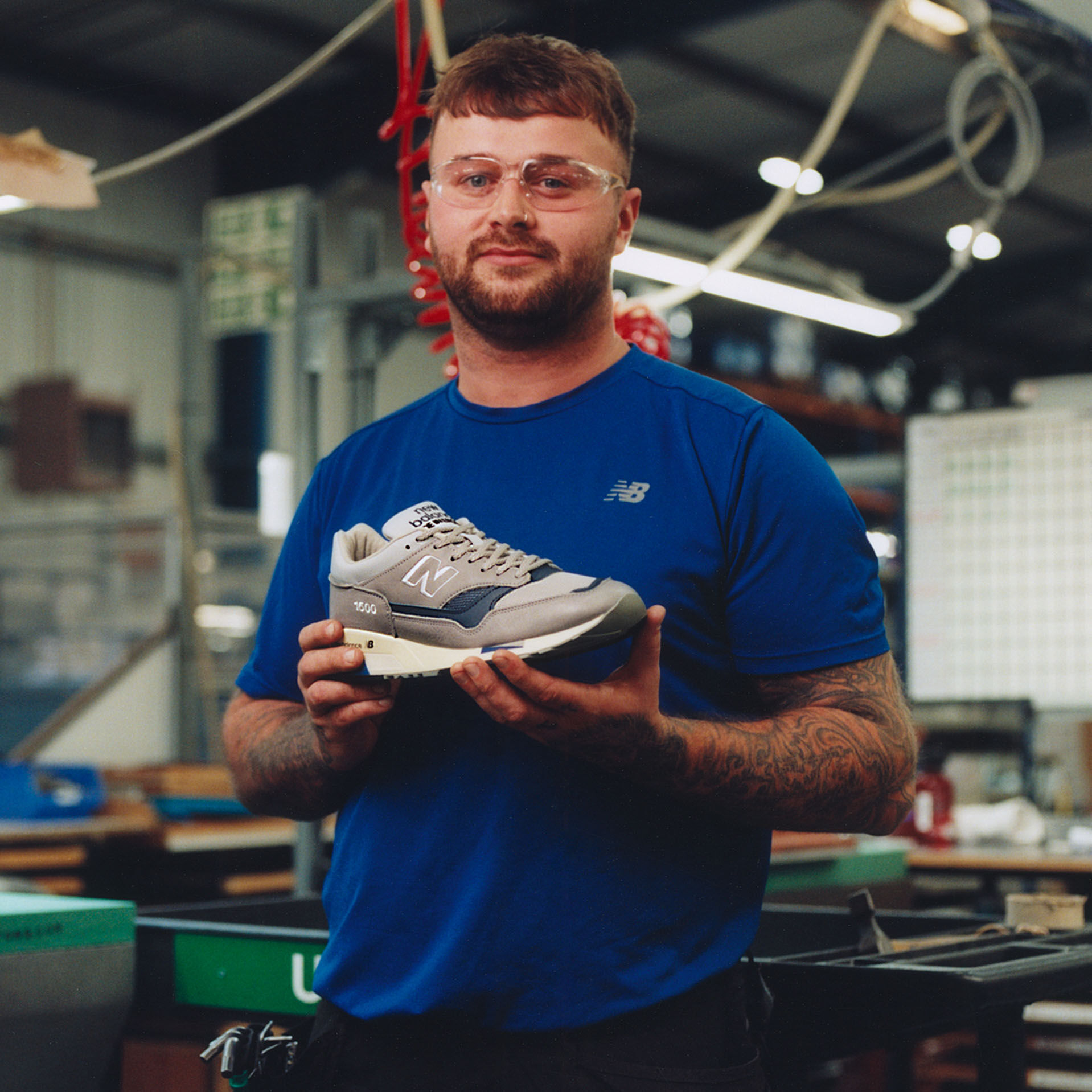 Male factory worker posing for camera while holding footwear product in factory environment